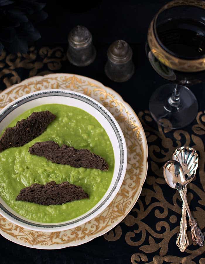 Ghoulishly Green Vegan Potato Soup in a gothic dinner place setting with red wine