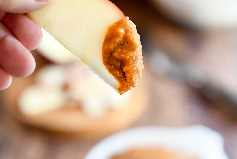 An apple slice dipped into the pumpkin dessert hummus