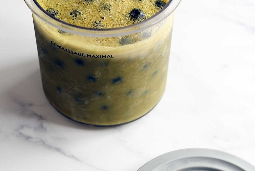 Matcha blueberry vegan ice cream frozen in a Ninja Creami pint before spinning.
